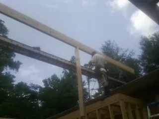 Carpenter setting a ridge beam over a new addition frame — Ice Dam Removal by Roofing Brothers in Waelder