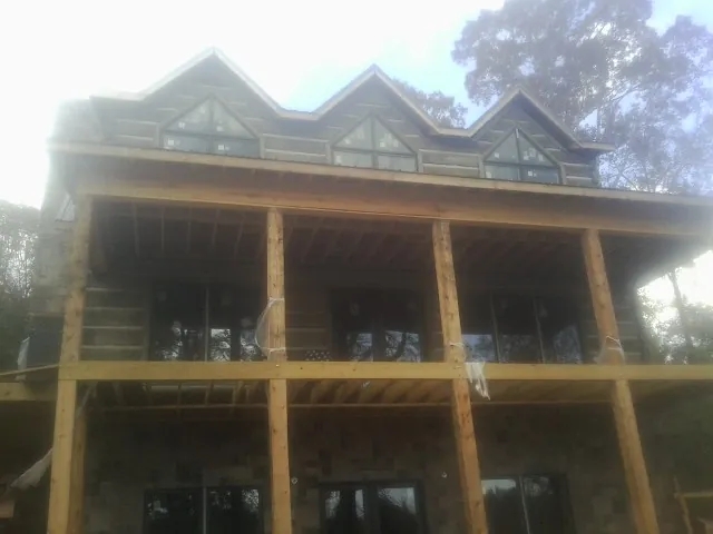 Dormers and porch framing on a large log home under construction — Roof Coating work by our crew in Waelder